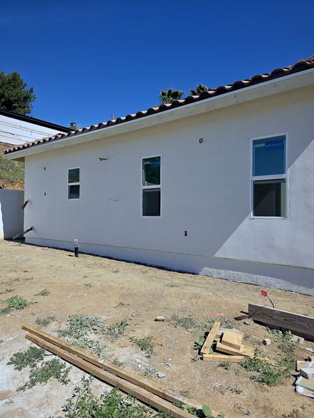 New-construction home with completed smooth white stucco and Spanish tile roof.