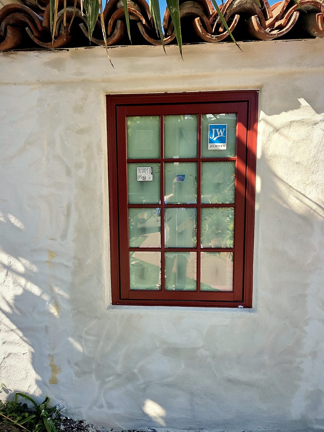 Same Spanish window after fresh smooth white stucco has been applied around the frame, blending into the original wall texture.